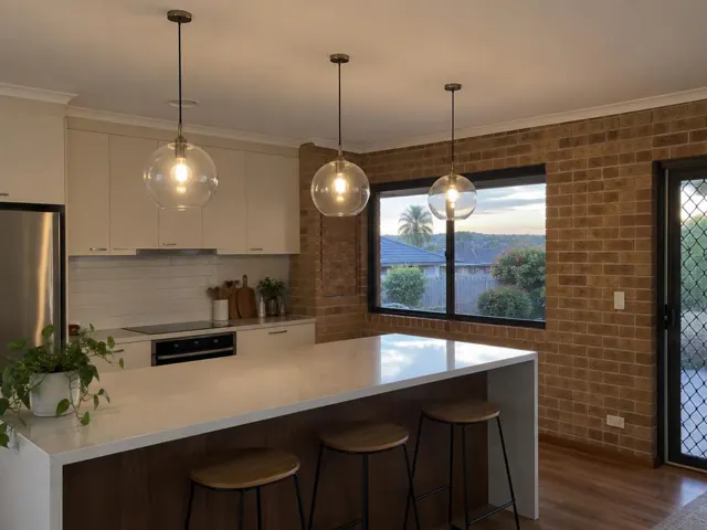 Three glass pendant lights above a kitchen island in a brick-walled home in Bateau Bay